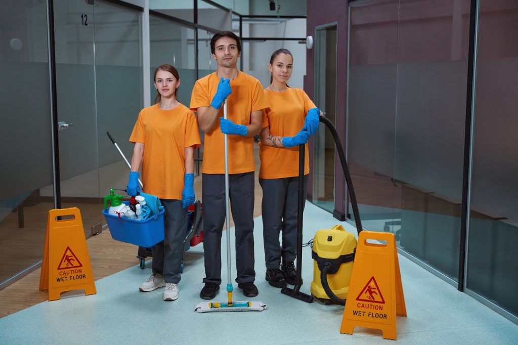 Young workers of cleaning company standing together with tools