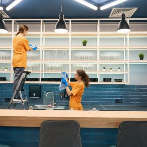 Cleaning company cleaners in process of general cleaning in kitchen in coworking