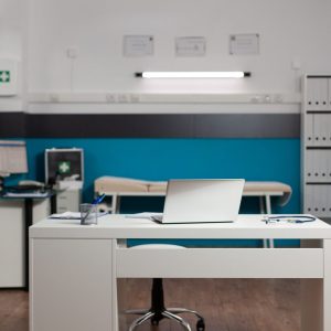 Empty doctors workplace room with desk and technology