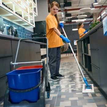 Young woman cleaning the floor with a mop